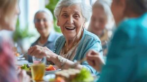 A caregiver gently assisting an older adult while they converse in a cozy, well-lit common room.
